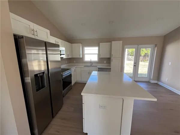 a kitchen with stainless steel appliances granite countertop a refrigerator a sink a stove and island