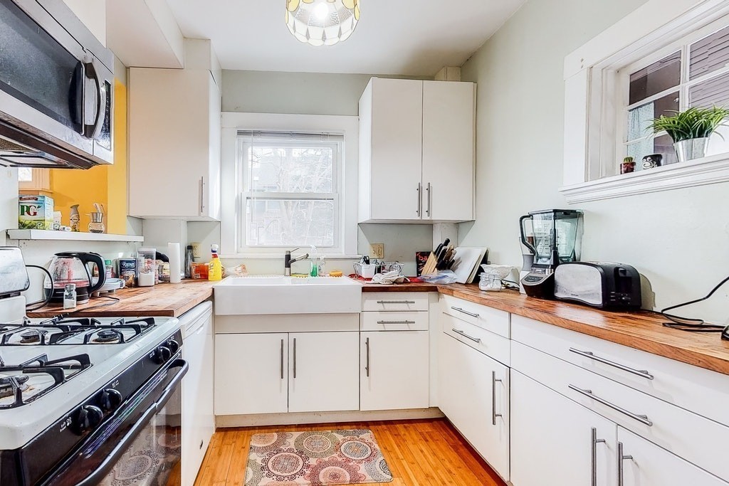8-10 Allston Street Newton, MA 02465 - Photo 22 of 42 a kitchen with stainless steel appliances white cabinets sink and a stove