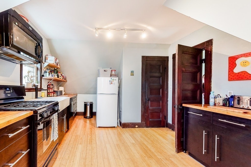 8-10 Allston Street Newton, MA 02465 - Photo 35 of 42 a kitchen with stainless steel appliances granite countertop a refrigerator a stove and a wooden cabinets