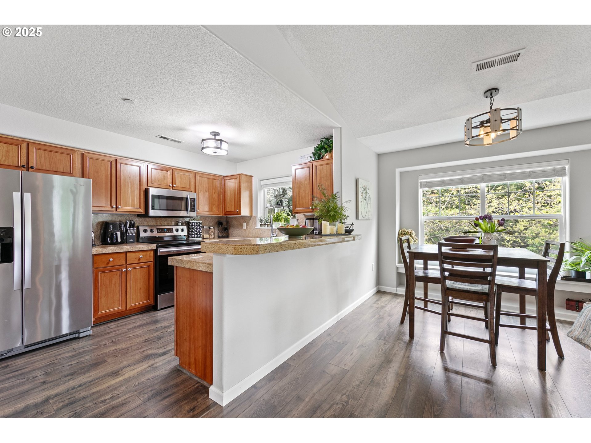 30366 Southwest Ruth Street, Unit 70 Wilsonville, OR 97070 - Photo 13 of 46 a kitchen with stainless steel appliances granite countertop a stove top oven a refrigerator a dining table and chairs with wooden floor