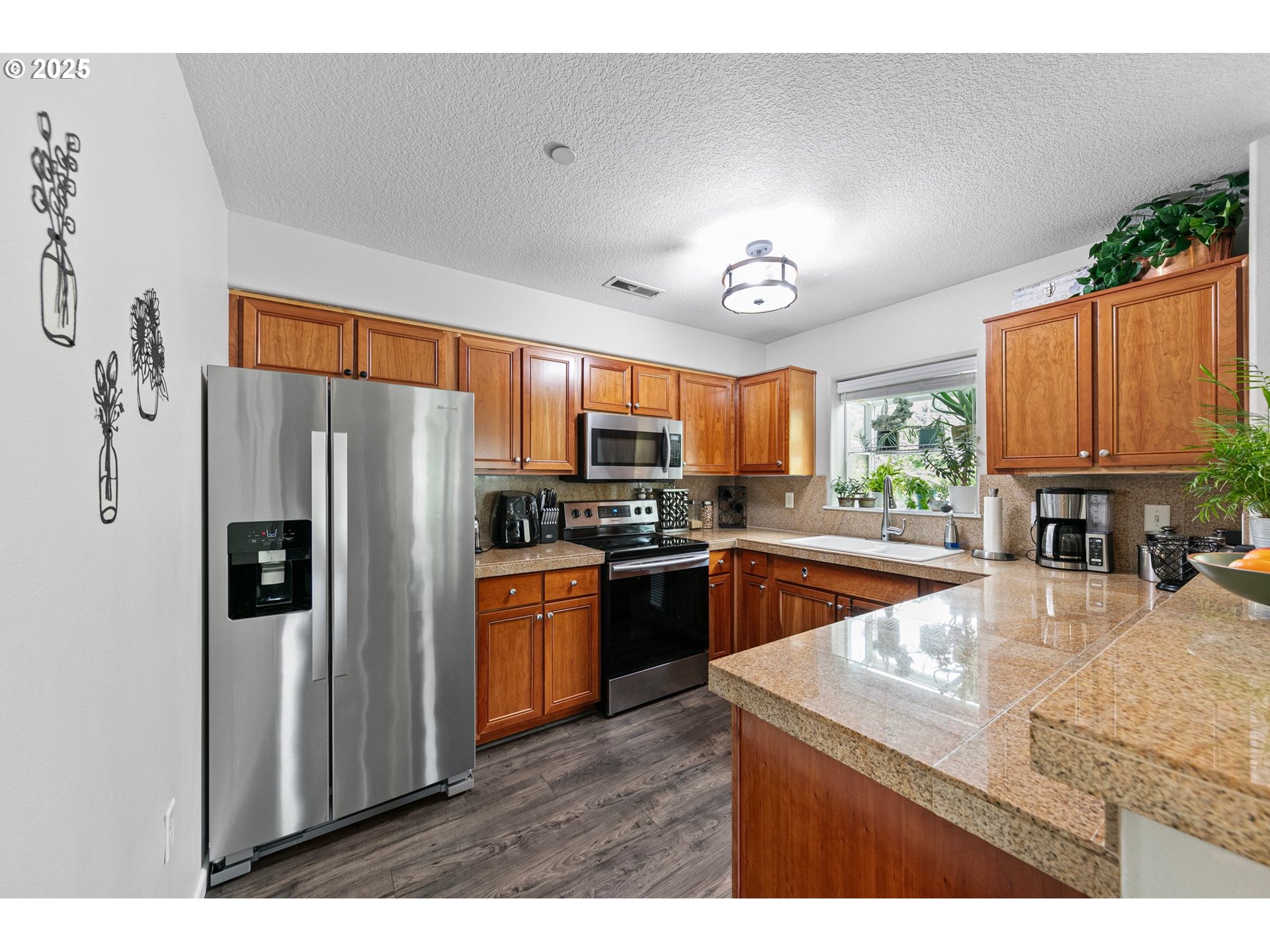 30366 Southwest Ruth Street, Unit 70 Wilsonville, OR 97070 - Photo 14 of 46 a kitchen with stainless steel appliances granite countertop a refrigerator a sink dishwasher a stove with wooden cabinets and floor