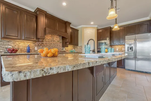a kitchen with granite countertop a sink a counter top space cabinets and stainless steel appliances