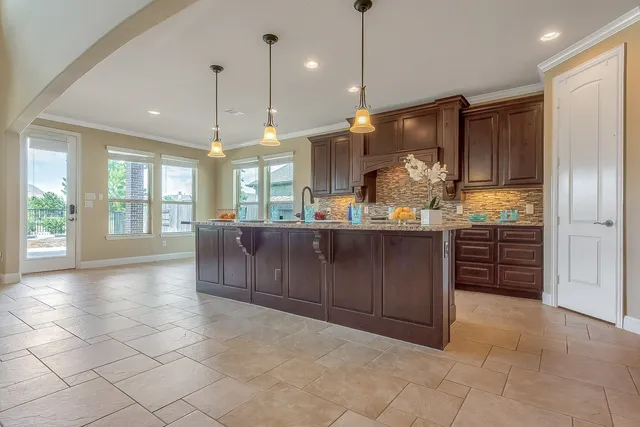 a open kitchen with stainless steel appliances granite countertop a refrigerator a sink a oven and a large window