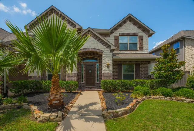 a view of a house with a small yard plants and palm trees
