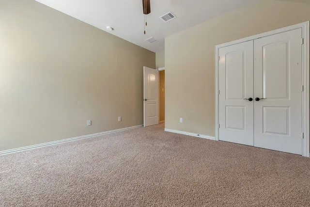 an empty room with a ceiling fan and window