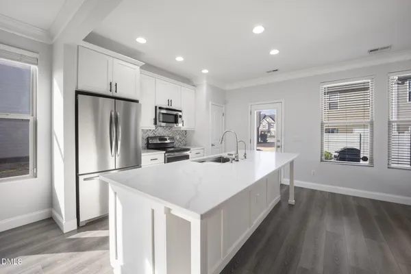 a kitchen with kitchen island a counter top space a sink stainless steel appliances and cabinets