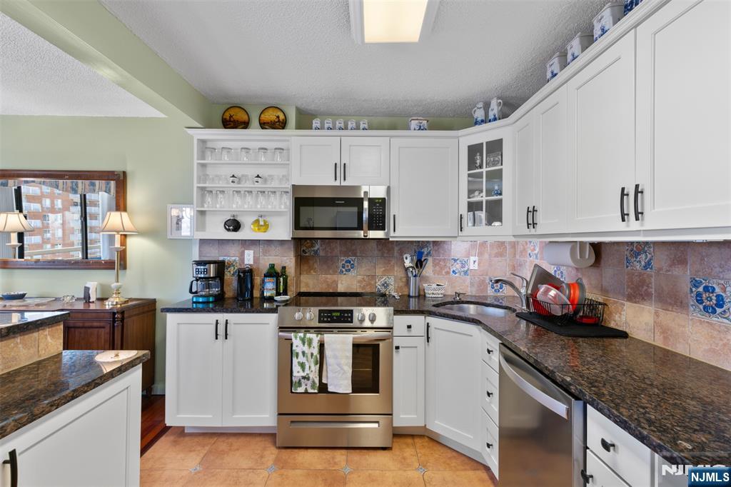 151 Prospect Avenue, Unit 9D Hackensack, NJ 07601 - Photo 11 of 38 a kitchen with stainless steel appliances granite countertop a sink and cabinets