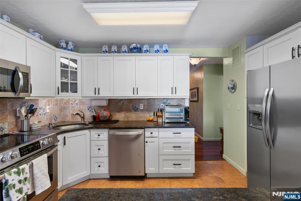 151 Prospect Avenue, Unit 9D Hackensack, NJ 07601 - Photo 13 of 38 a kitchen with stainless steel appliances a sink stove and refrigerator