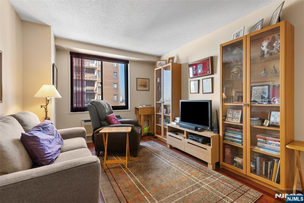 151 Prospect Avenue, Unit 9D Hackensack, NJ 07601 - Photo 14 of 38 a living room with furniture a flat screen tv and a floor to ceiling window