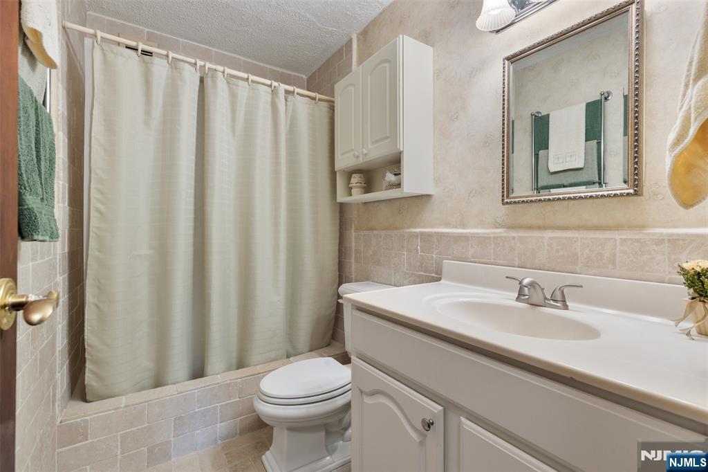 151 Prospect Avenue, Unit 9D Hackensack, NJ 07601 - Photo 26 of 38 a bathroom with a sink a toilet and shower curtain