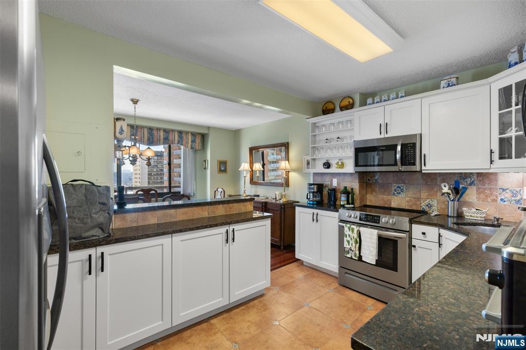 151 Prospect Avenue, Unit 9D Hackensack, NJ 07601 - Photo 10 of 38 a kitchen with stainless steel appliances granite countertop a stove a sink and a microwave
