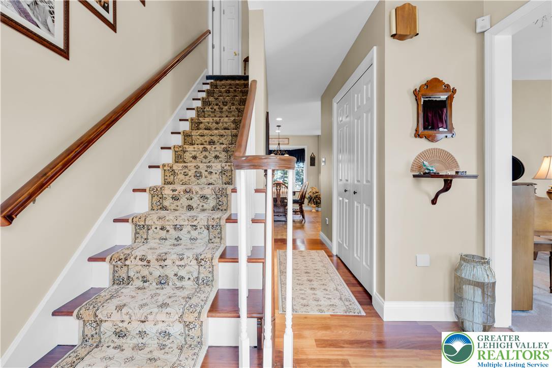 4059 Old Sentry Road Allentown, PA 18104 - Photo 4 of 39 A graceful staircase with a patterned runner leads to the upper level, complementing the warm wooden flooring.