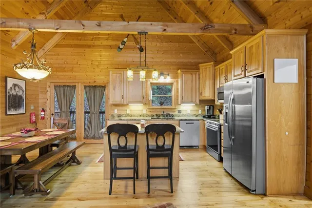 a kitchen with stainless steel appliances granite countertop a refrigerator a stove a sink dishwasher and white cabinets with wooden floor