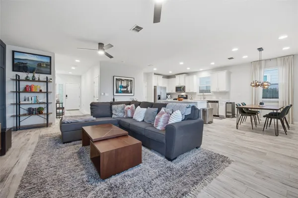 a large white kitchen with wooden floor and stainless steel appliances
