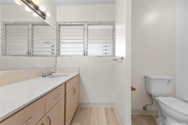 a bathroom with a granite countertop sink a toilet and a window