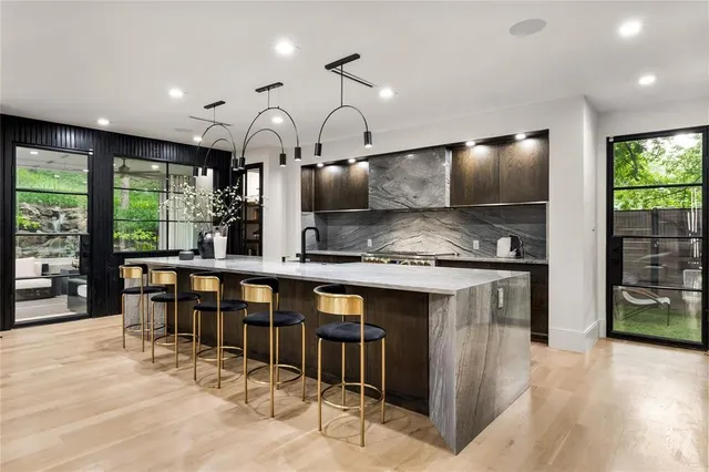 a kitchen with stainless steel appliances kitchen island granite countertop a table chairs in it and wooden floors