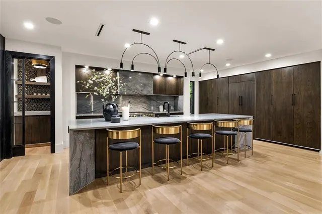 a kitchen with kitchen island granite countertop a table chairs sink and cabinets