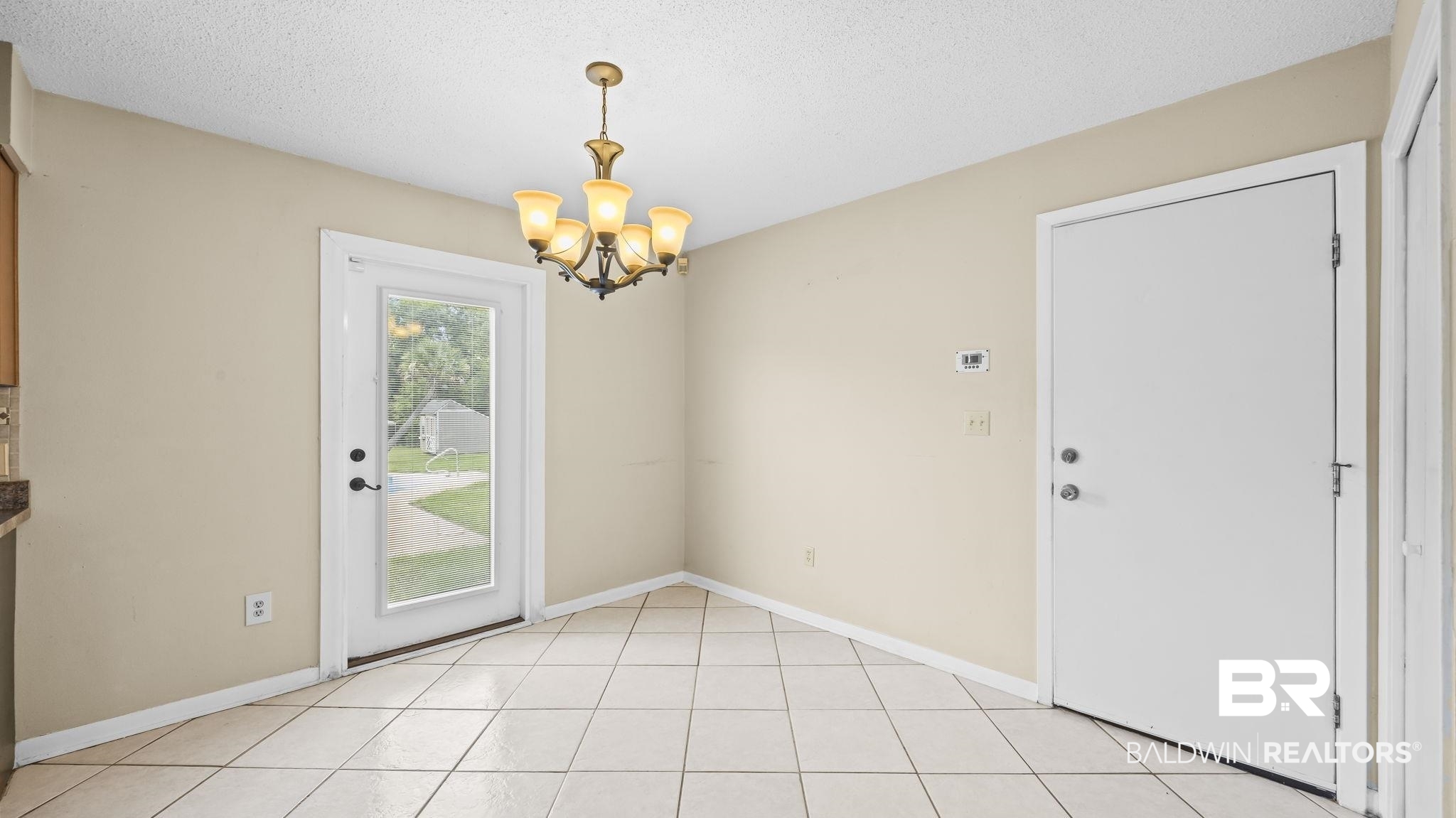 15096 Highland Circle Foley, AL 36535 - Photo 14 of 52 Dining area featuring light-toned tile flooring, neutral wall tones, a five-light chandelier, a white exterior door with full-length glass, and a solid white interior door