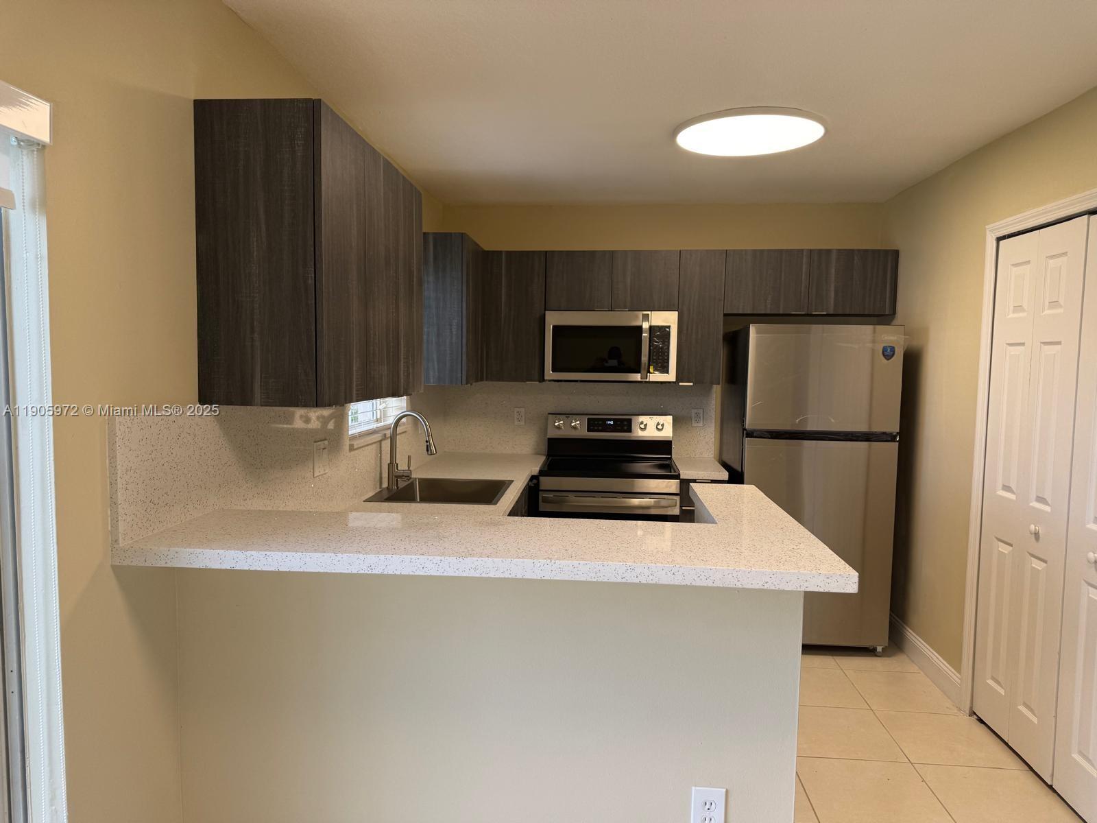 1261 Southeast 31st Court, Unit 10653 Homestead, FL 33035 - Photo 4 of 10 a kitchen with a refrigerator a stove top oven a sink and dishwasher