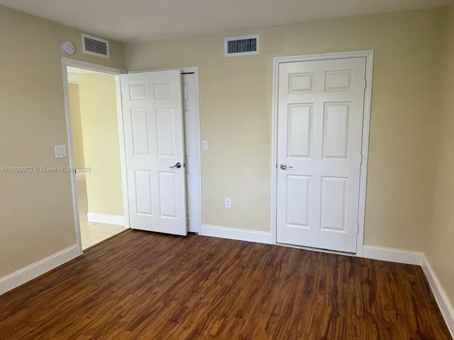 an empty room with wooden floor and closet area