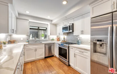 a kitchen with granite countertop a sink stove and refrigerator