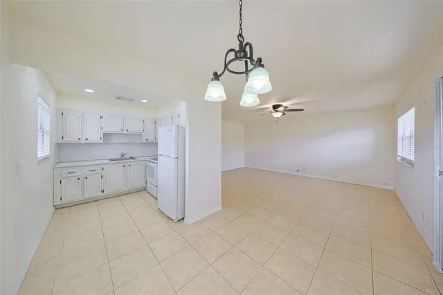 a view of an empty room with chandelier fan