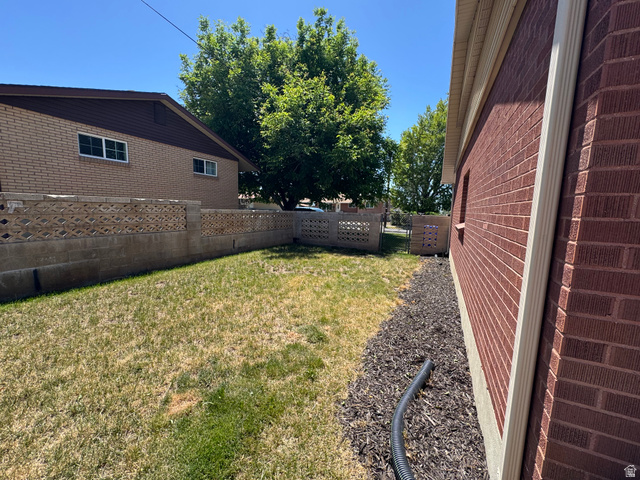 1611 South 75 East Bountiful, UT 84010 - Photo 4 of 23 Expansive backyard featuring a manicured lawn, brick perimeter fencing with decorative block, and established trees