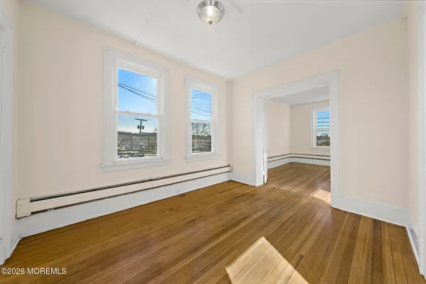 a view of empty room with wooden floor and fan