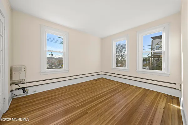 a view of an empty room with a window and wooden floor