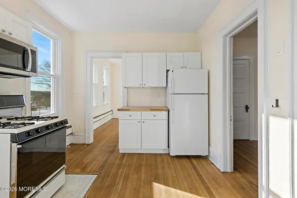 a kitchen with a refrigerator stove and wooden floor