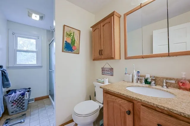 a bathroom with a granite countertop sink a mirror and a toilet