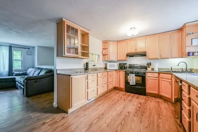a kitchen with granite countertop wooden floors a stove and a microwave