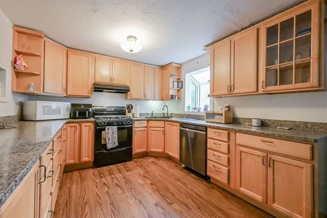 a kitchen with stainless steel appliances granite countertop a stove a sink dishwasher and a microwave oven with cabinets