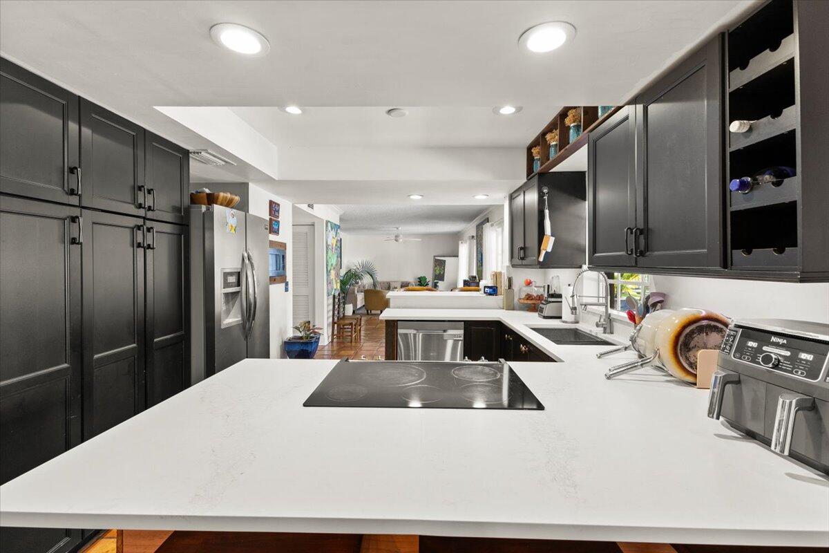 3179 Hoy Lake Road Wellington, FL 33467 - Photo 10 of 43 a kitchen with stainless steel appliances kitchen island granite countertop a refrigerator a stove and a sink with wooden cabinets