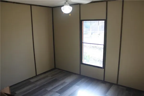 an empty room with wooden floor cabinet and windows