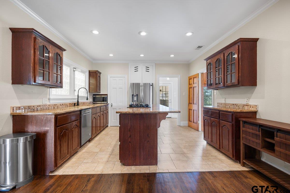 1609 Old Nacogdoches Road Henderson, TX 75654 - Photo 13 of 48 a large kitchen with stainless steel appliances granite countertop a stove a sink dishwasher a microwave oven and a dining table with wooden floor
