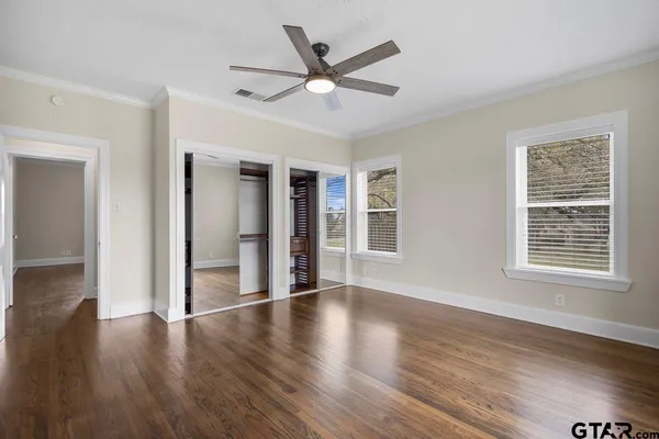 an empty room with wooden floor closet and windows