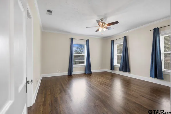 a view of an empty room with wooden floor and window