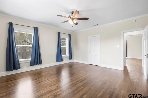 a view of an empty room with window and wooden floor