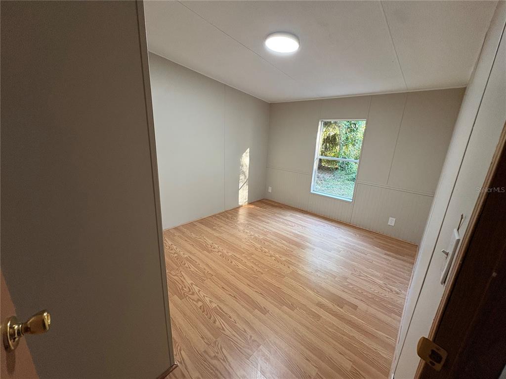 28492 Sentinel Street Nobleton, FL 34661 - Photo 16 of 23 an empty room with wooden floor and windows