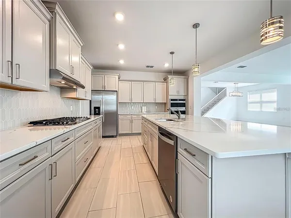 a large kitchen with stainless steel appliances granite countertop a sink a stove and a refrigerator