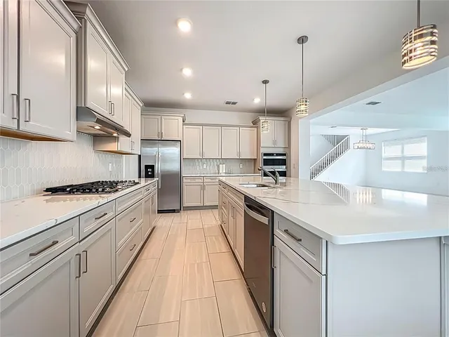 a large kitchen with stainless steel appliances granite countertop a sink a stove and a refrigerator