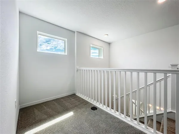 an empty room with windows and chandelier fan