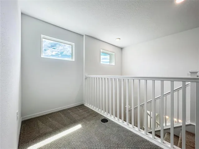 an empty room with windows and chandelier fan