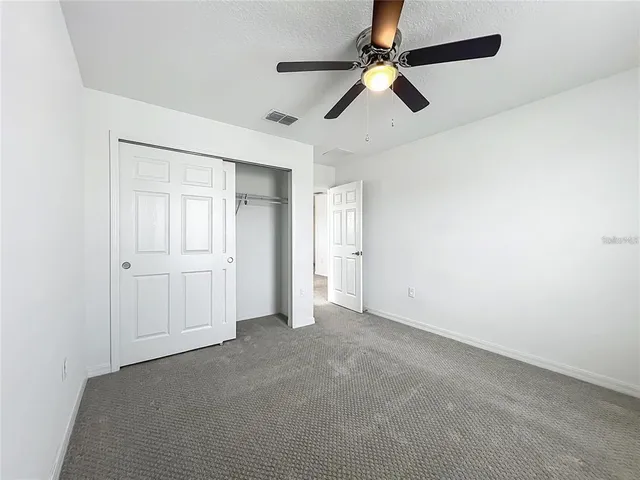 an empty room with a ceiling fan and windows