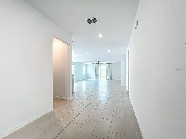 an empty room with wooden floor staircase and windows