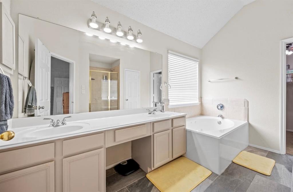 4524 Lodestone Lane Fort Worth, TX 76123 - Photo 6 of 9 Full bath featuring double vanity, a bath, vaulted ceiling, a shower stall, and dark tile patterned flooring