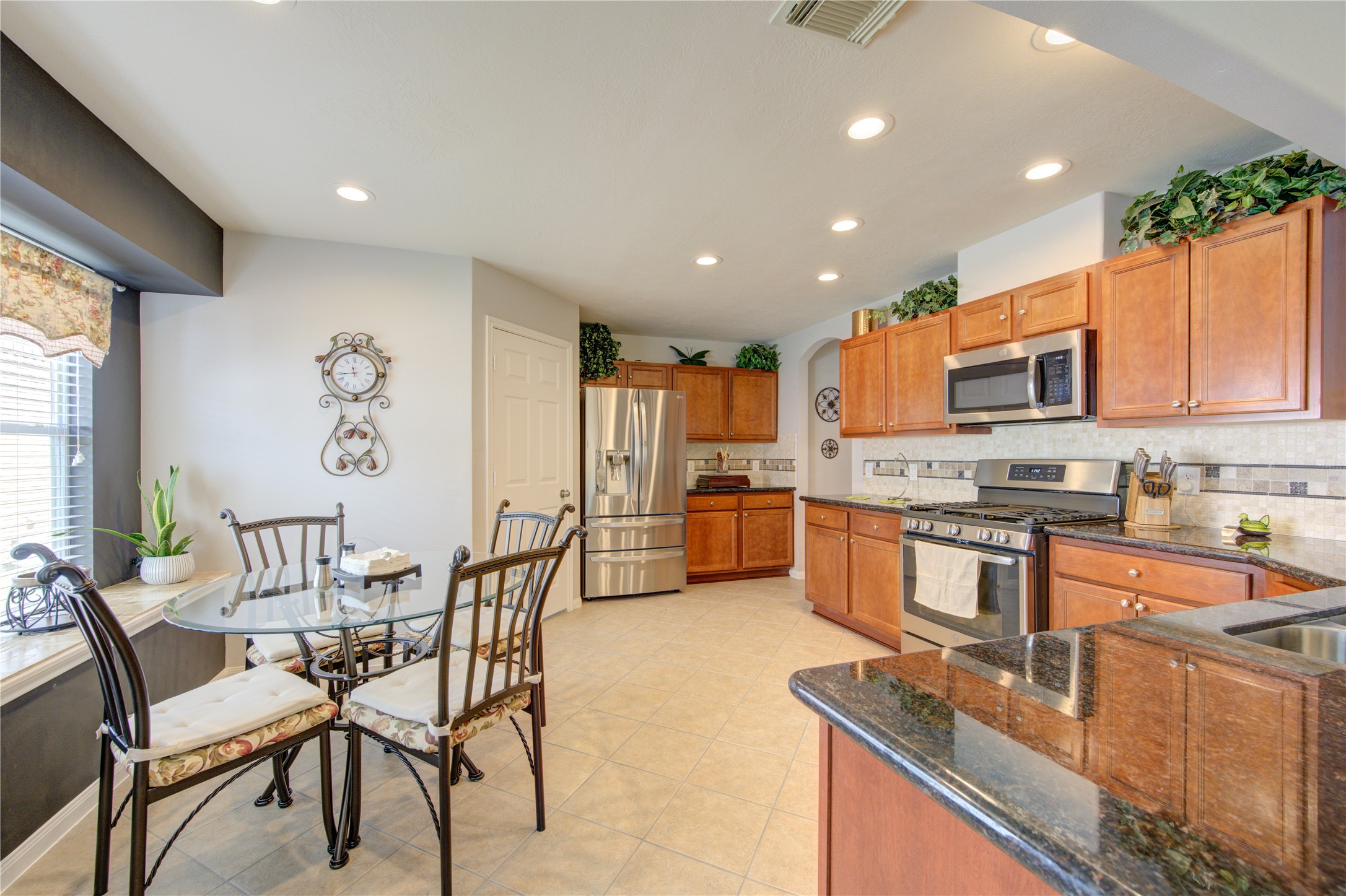 25215 Hazel Ranch Drive Katy, TX 77494 - Photo 11 of 32 a kitchen with stainless steel appliances granite countertop a stove top oven a sink dishwasher a dining table and chairs with wooden floor