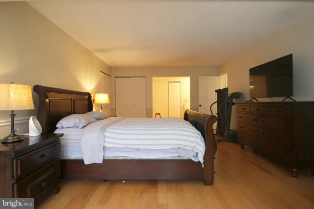 a bedroom with a bed and flat tv screen on the dresser