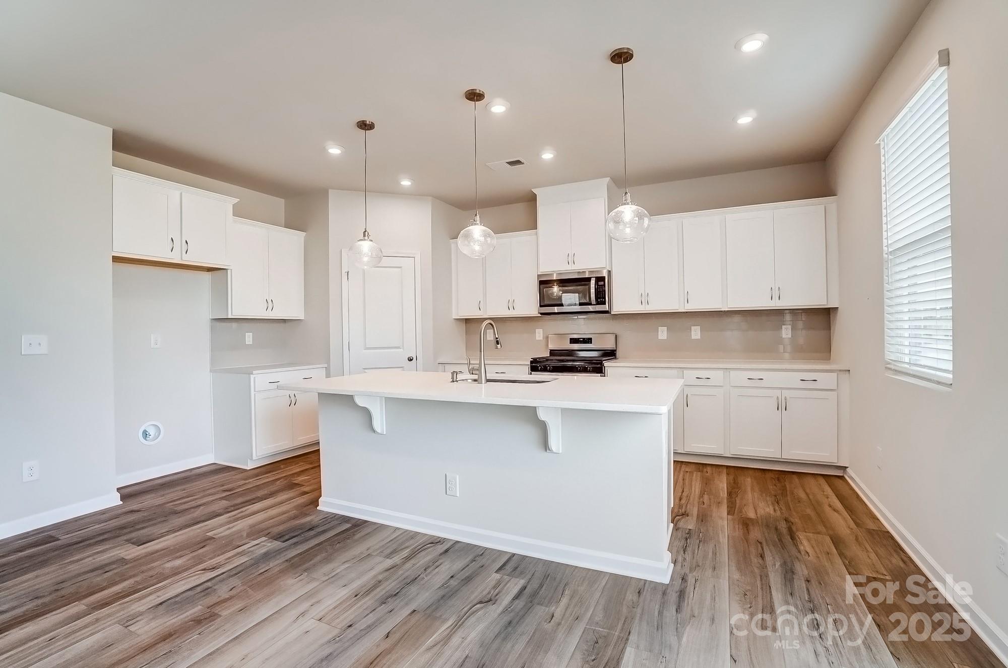 1471 Honey Trail Monroe, NC 28112 - Photo 9 of 27 a kitchen with wooden floors white cabinets appliances and a window